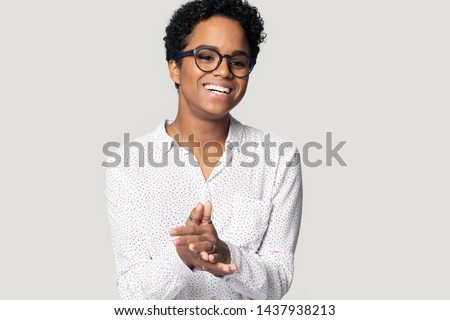 Happy african American millennial woman in glasses isolated on grey studio background laugh talking with someone, smiling biracial black girl in spectacles feel positive show white healthy teeth