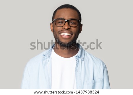 Headshot portrait of smiling african American man wearing glasses and shirt look at camera laughing, happy black millennial male in spectacles isolated on grey studio background posing for picture