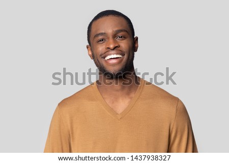 Headshot portrait of smiling african American millennial man in tshirt isolated on grey studio background, happy black male look at camera feel satisfied or pleased laughing posing for picture Royalty-Free Stock Photo #1437938327