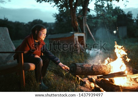 A girl near the fire throws up firewood nature evening rest