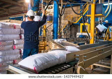 Worker loading Rows or stacks of white sack bags at large warehouse in modern factory. Packaging in factory or warehouse
