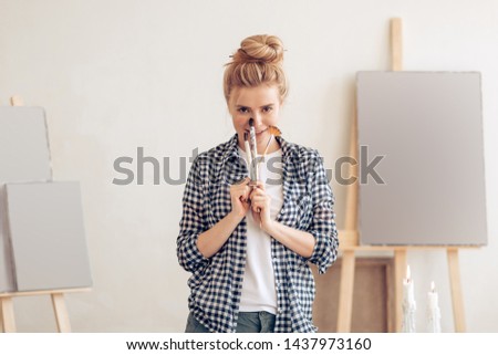 young attractive cheerful woman holding brushes and posing in art studio. close up photo. happiness, job , free time , spare time