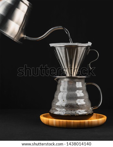 The process of brewing coffee in pour over, filter coffee, a glass teapot on a wooden tray on a dark background. Royalty-Free Stock Photo #1438014140