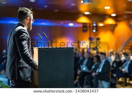 Speaker giving a talk on corporate business conference. Unrecognizable people in audience at conference hall. Business and Entrepreneurship event. Royalty-Free Stock Photo #1438041437
