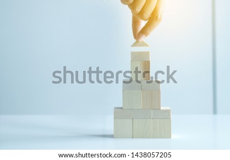 Hand woman holding block wood stack house model on white background,Real estate growth up concept