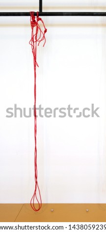 Red rope hanged on black metal construction, white wall background