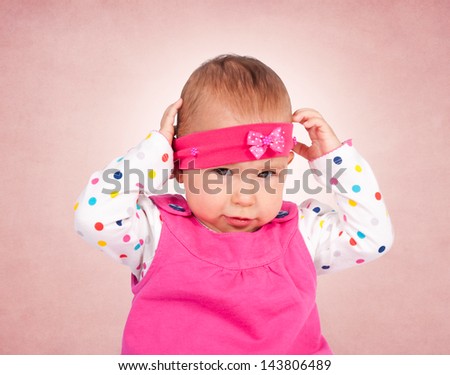 Little baby girl holding hand on her head