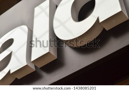 sign or logo on an exterior wall of a commercial building. The capital letters in the sign are white illumination. 