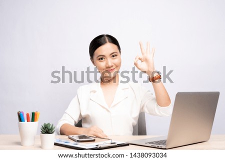 Happy woman showing OK gesture at office isolated over background