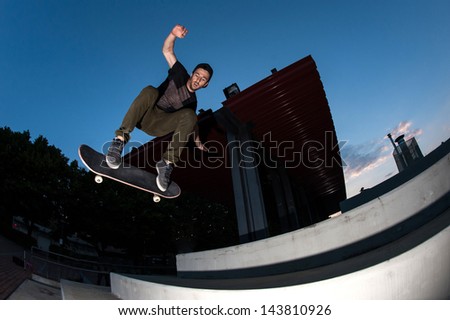 Skateboarder jump in the street from below, night time.