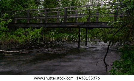 Old bridge over the waters of the northern river in the dark taiga