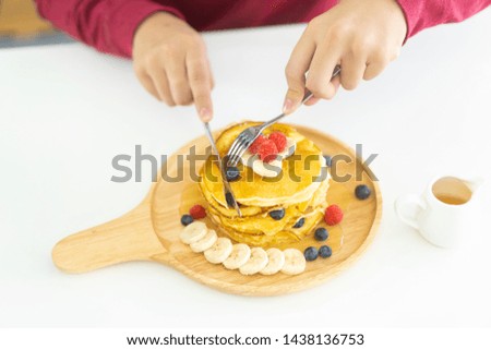 Teenager high school man eat Pancakes with berries and maple syrup in breakfast.
