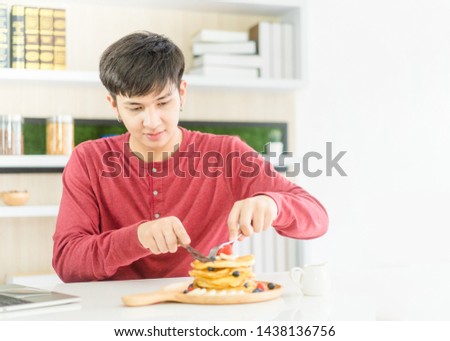 Teenager high school man eat Pancakes with berries and maple syrup in breakfast.