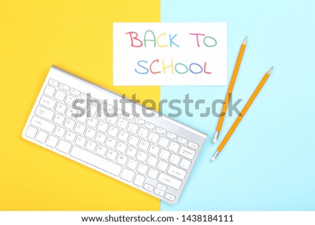 Text Back To School with computer keyboard and pencils on colorful background