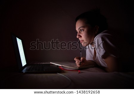 woman working at home on laptop in bed light from the screen