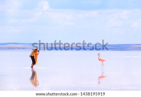 Young girl taking pictures of flamingo in a salt lake Tuz Golu, Turkey