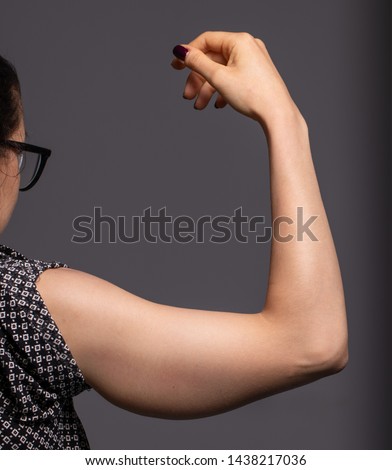 A closeup view on the arm of a young Caucasian woman with sagging fat beneath the triceps. A common location for arm lift surgery, bingo-wing correction. Royalty-Free Stock Photo #1438217036
