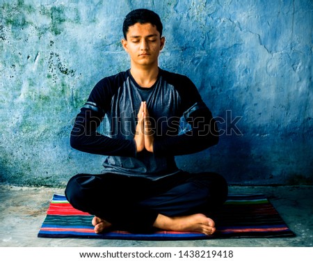 Easy Pose or Sukhasana performed by a young man doing on the colorful mat by wearing black attire. Royalty-Free Stock Photo #1438219418