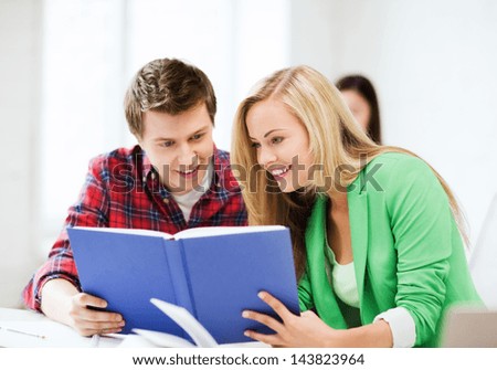 picture of smiling student girl and guy reading book at school
