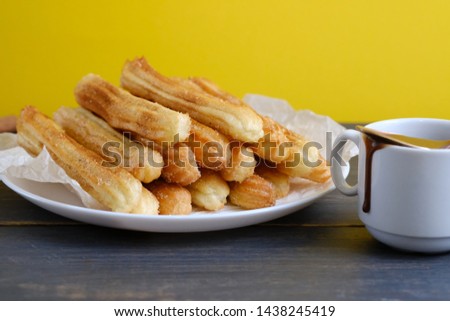 A bunch of Spanish churros and chocolate in a cup on the table. Spanish dessert Churros with sugar, cinnamon and chocolate.