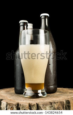 Bottles of beer and beer mug on stump. White isolated studio shot.