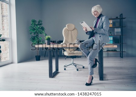 Full length side photo of aged business lady arms e-reader search information project lean table office wear specs costume suit jacket