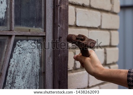 man is hammering a nail in an old wooden window