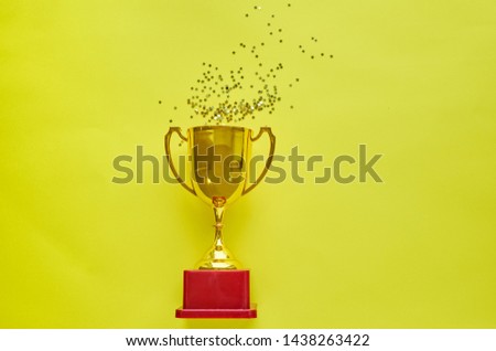 Gold winners trophy with golden shiny stars on yellow background