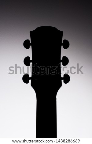 Acoustic guitar neck silhouette in studio.
