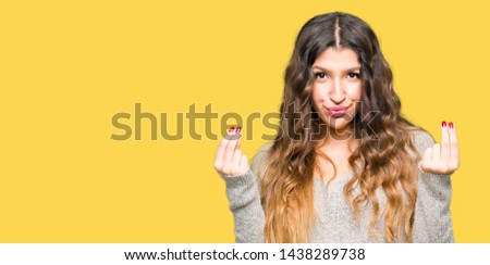 Young beautiful woman wearing winter dress Doing money gesture with hand, asking for salary payment, millionaire business