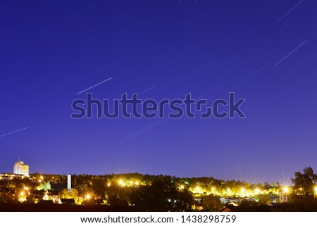 Star traces  in the night sky over the city.
