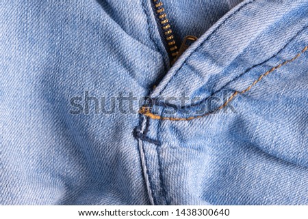 Blue denim. Cotton fabric, jeans. Creative vintage background. Pocket and zipper. The line is of poor quality. Cheap item