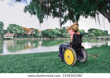 Disabled child on wheelchair is play and learn by the pond in the city outdoor park , Special children's lifestyle, Life in the education age of special need children, Happy disability kid concept.