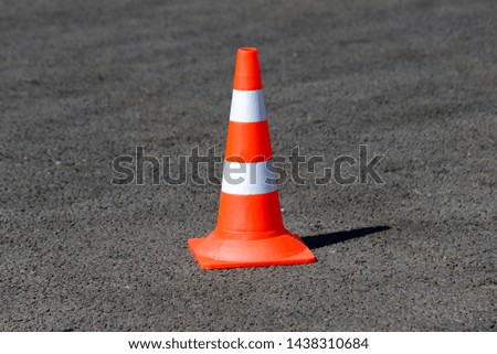 An orange traffic cone on the asphalt road