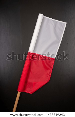 Polish flag on a dark table. A flag attached to a wooden spar. Dark background.