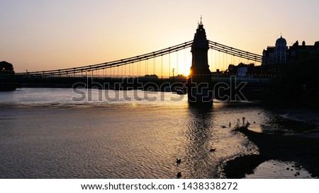 Looking in to the sunset over the river Thames with a the silhouette of Hammersmith Bridge, London, UK
