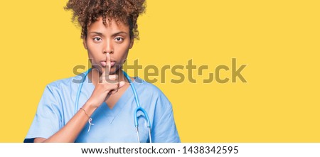Young african american doctor woman over isolated background asking to be quiet with finger on lips. Silence and secret concept.