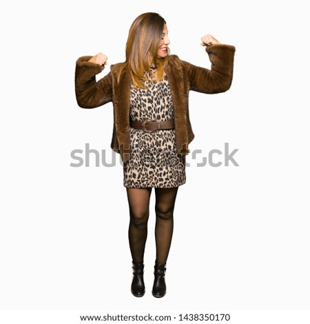 Beautiful middle age elegant woman wearing mink coat showing arms muscles smiling proud. Fitness concept.