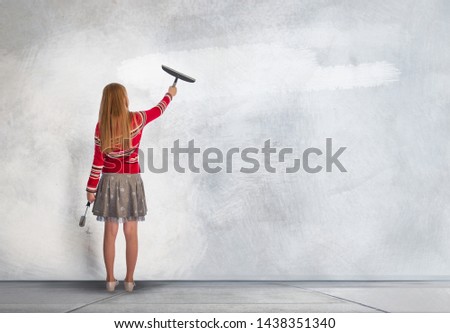 Little girl standing next to the wall and paints over. Space for text or image. 