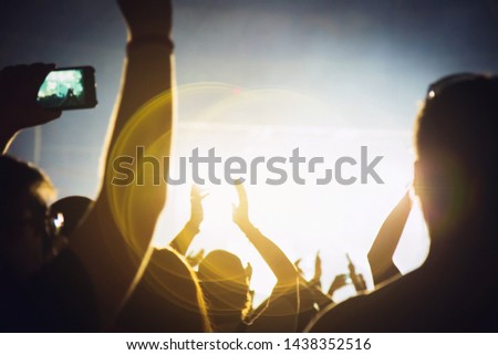 Silhouette of a concert crowd. The audience applauds the musicians on stage. The bright spotlight and dancing people.