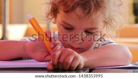 Child holding color pen and drawing outside concentrated and focused.