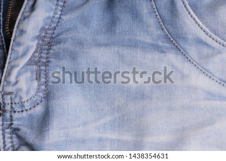 Blue denim. Cotton fabric, jeans. Creative vintage background. Pocket and zipper. The line is of poor quality. Cheap item