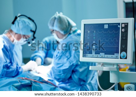 A surgeon's team in uniform performs an operation on a patient at a cardiac surgery clinic. Modern medicine, a professional team of surgeons, health. Royalty-Free Stock Photo #1438390733
