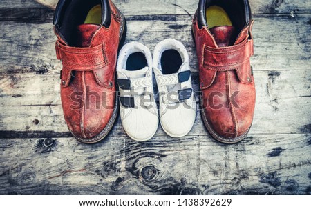 pair of shoes on wooden background. Father boots and baby shoes on wooden background, fathers day. Daddy's boots and baby's shoes, fathers day concept.