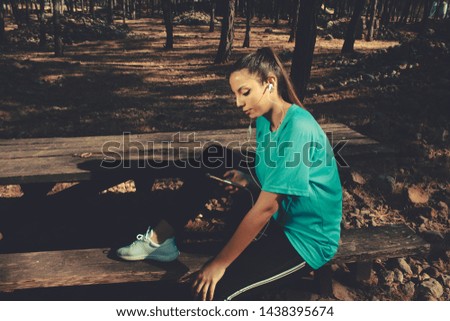Girl with sport clothes sitting and checking her mobile phone