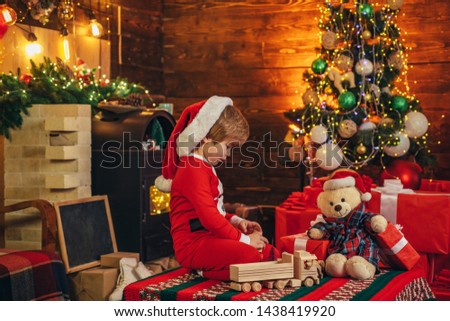 Christmas miracle and new year feelings. A little boy in warm clothes sitting and playing with wooden toys gift. Open-ended Games. First memory of childhood