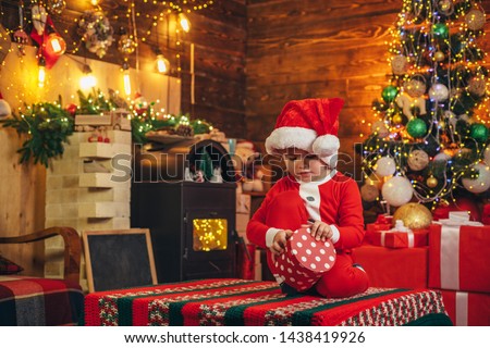 Happy child with christmas gift box. A little boy in warm clothes sitting and playing with wooden toys gift. Christmas miracle and new year feelings. Open-ended Games. First memory of childhood