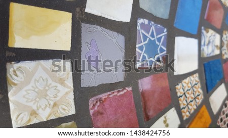 Colorful mosaic made from different pieces of vintage broken tiles. Ceramic glossy surface of tiles and dark cement joints between tile pieces. Patterned background. Retro style home decor. 
