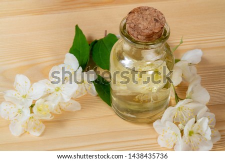 flowers of philadelphus somewhere called jasmine or mock orange and a bottle of oil on a wooden table