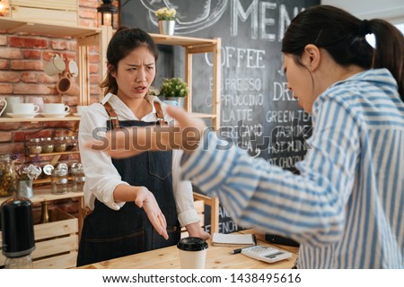emotional female customer arguing with staff girl at bar counter. Unsatisfied visitor angry about service in cafe shop. woman client dislike coffee drink and yelling at barista lady in morning store Royalty-Free Stock Photo #1438495616